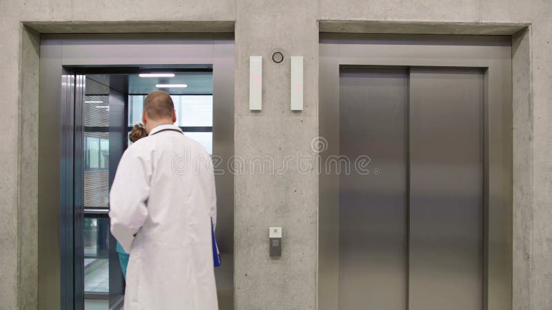 Doctor and nurse interacting with each other and entering in lift stock video footage